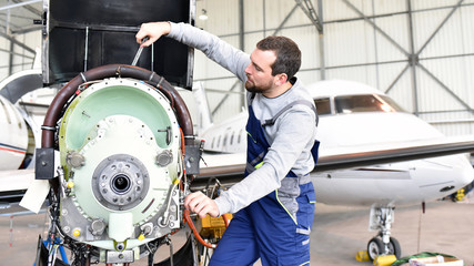 Fluggerätemechaniker repariert Triebwerk von Flugzeug im Hangar // workers repairs engine from the...
