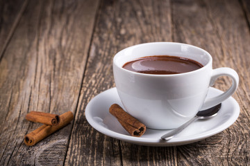 White cup of delicious hot chocolate with candies on table.