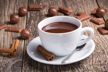 Papier Peint photo autocollant Chocolat Tasse blanche de délicieux chocolat chaud avec des bonbons sur la table.