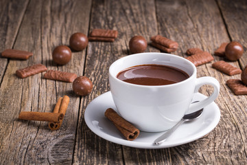 White cup of delicious hot chocolate with candies on table.