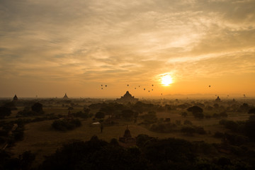 Hot air balloon float over group of  silhouette ancient temple with scenic sunrise orange sky at Old Bagan , Myanmar