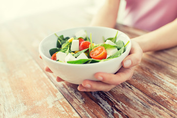 close up of young woman hands showing salad bowl