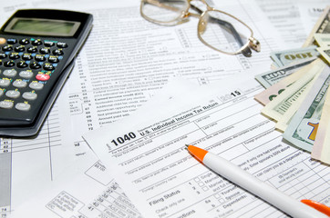 Tax form with pen, glasses, and calculator