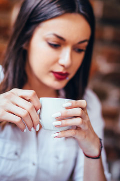 Pretty young woman drinking a cup of coffee/  indoors portrait of a businesswoman