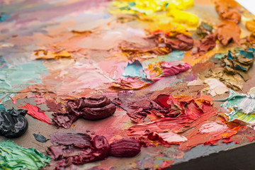 used brushes in an artist's palette of colorful oil paint for dr