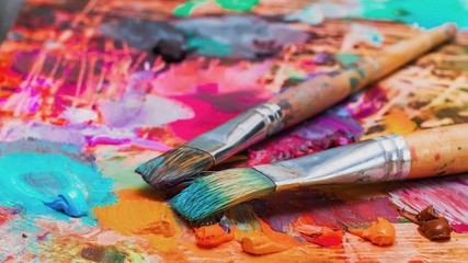 Obraz premium Used brushes on an artist's palette of colorful oil paint
