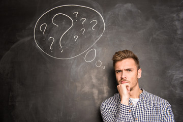 Young man against the background of chalkboard thinking about th