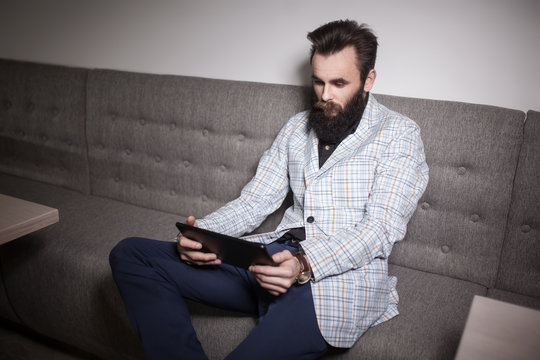 bearded man in suit and with laptop sitting in cafe and browsing internet