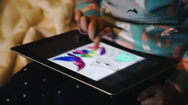 Child's hand leafing through pictures on the tablet