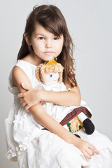 Adorable little girl cuddles and plays with her doll