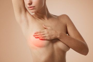 Closeup cropped portrait young woman with breast pain touching chest colored isolated on...