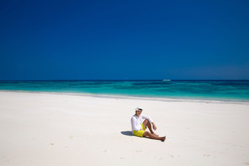 Fototapeta na wymiar Summer beach. Relax. Successful handsome man in hat resting on e