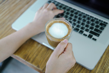 Closeup of business woman hand typing on laptop keyboard and cof