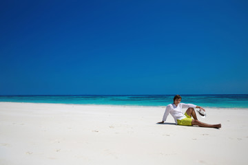 Fototapeta na wymiar Freedom. Beach. Handsome man in hat resting on exotic seashore w