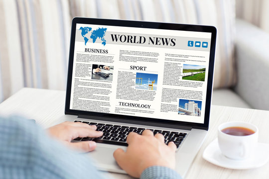 man holding notebook with world news site on the screen
