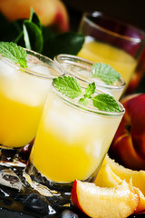 Cool summer peach juice with crushed ice, fresh peaches with lea