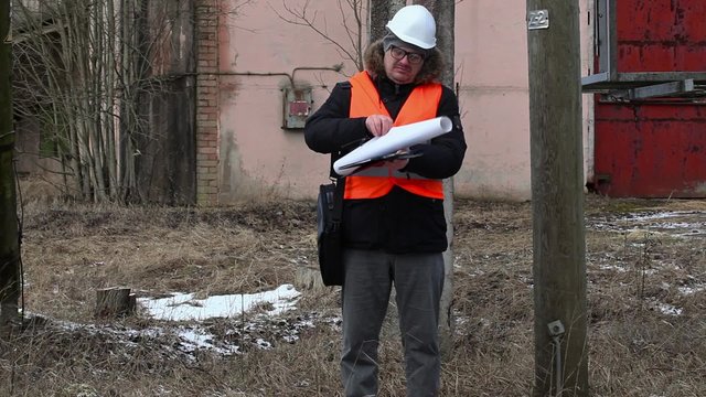 Engineer with documentation near powerline
