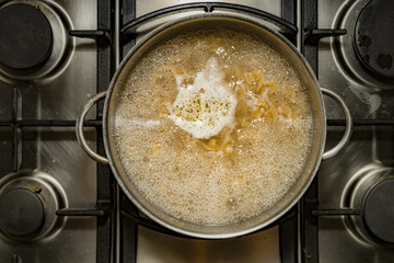 Cooking fusilli pasta in boiling water in a metal pan on a stove