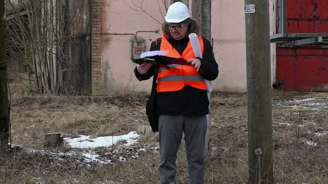Engineer checking documentation near powerline