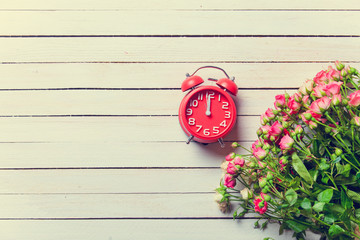 Beautiful bouquet of roses and retro alarm clock