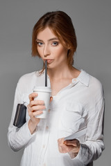 red hair girl drinks through straw from the glass