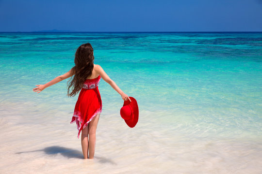 Happy woman enjoying on exotic beach in summer by tropical blue