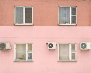Fototapeta na wymiar old city house painted pink - windows and conditioners