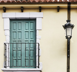 balcony with green doors and classic lamppost on yellow facade