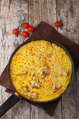chicken pilaf in a frying pan on wood table
