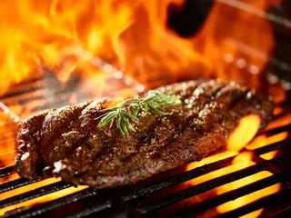 Poster grilling a juicy flat iron steak over open flame © Joshua Resnick