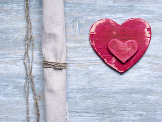 Two wooden heart shapes on a wooden background with linen fabric