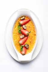 white dish with a cream brulee with raspberries, blueberries, ga
