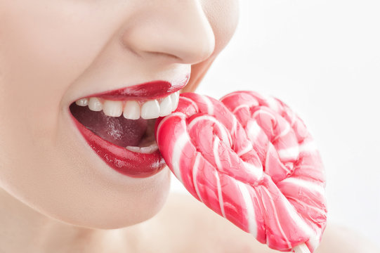 Cute young woman is eating sweet candy