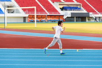 Fototapeta premium Boy runnin on blue track