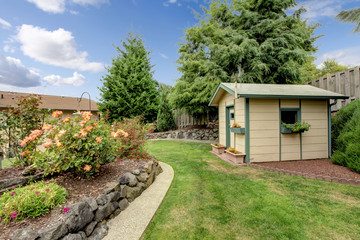 Fototapeta na wymiar Back yard with grass walkway, small gardening shack, and layered