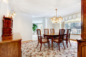 Dinning room with floral patterned rug, deep toned wood and chan
