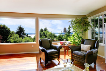 Two leather lounge chairs and large windows in corner of living