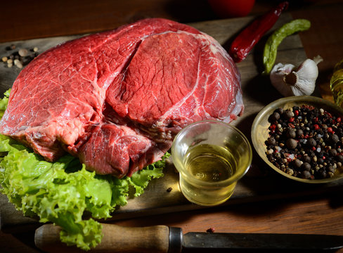raw steak on the wooden background with spices and herbs
