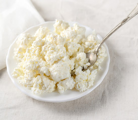 Plate of homemade cottage cheese on white tablecloth. 