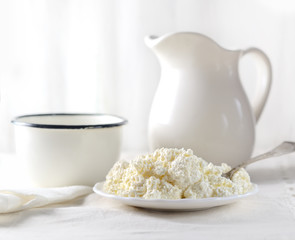 Dish of cottage cheese, a mug and a pitcher on a white background