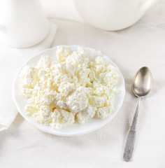 Plate of homemade cottage cheese on white tablecloth. 