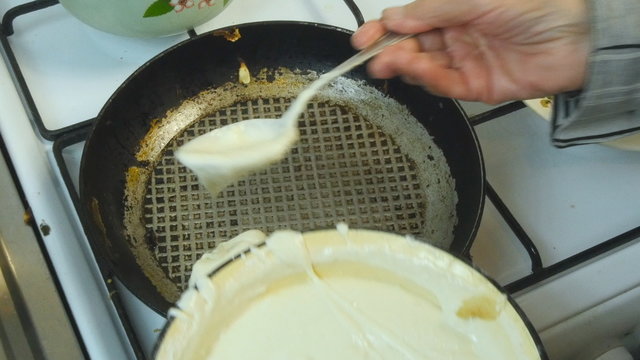 Grandmother fries pancakes in a frying pan