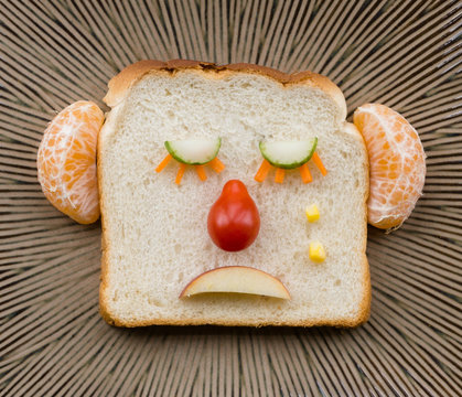 Funny Sad Bread Face Made With Fruit And Vegetables On Ceramic Plate