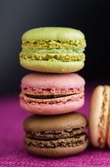 Stack of macaroons on pink jute tablecloth black background closeup