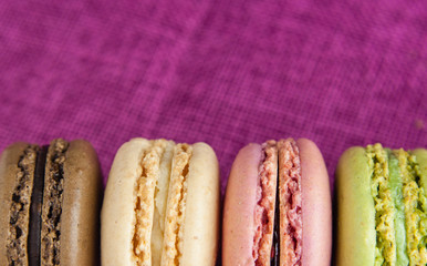 Boarder of macaroons on pink jute tablecloth closeup space for text