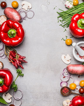 Fototapeta Red paprika and diverse vegetables and cooking ingredients on gray stone background, top view, frame, vertical. Vegetarian food and healthy lifestyle concept.