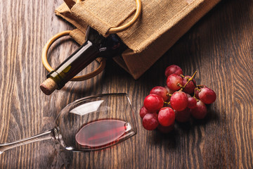 Glass with wine, a bottle and bunch of grapes, wooden background