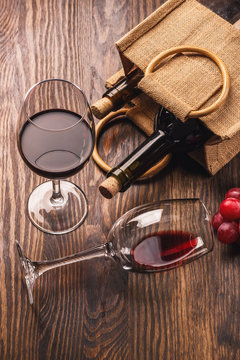 Glasses with wine, bottles and bunch of grapes, wooden background