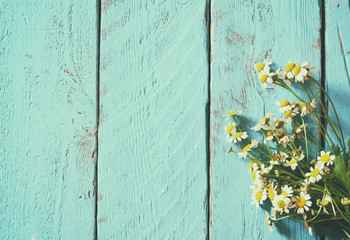 top view image of daisy flowers on blue wooden table. vintage filtered and toned
