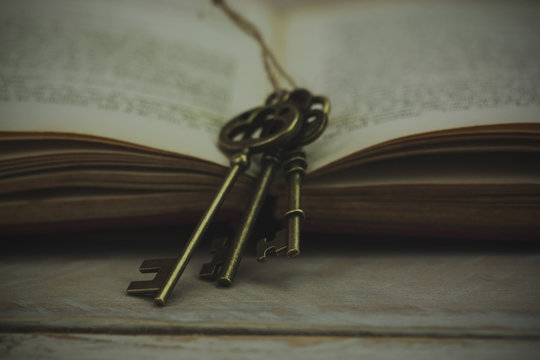 Antique keys with book on wooden background